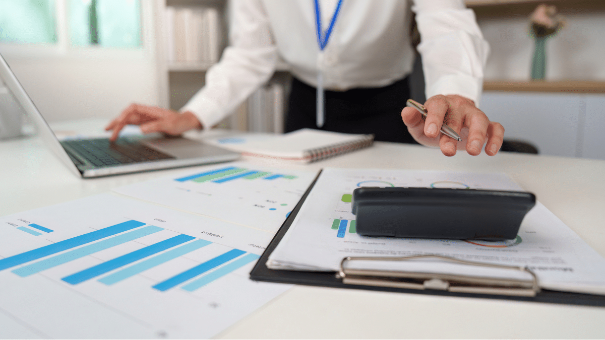 Business owner reviewing financial charts and reports on a desk with a laptop and calculator